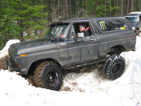 1979 Ford Bronco - A driver navigates a snowy trail in a modified Ford Bronco, with another vehicle following closely behind.