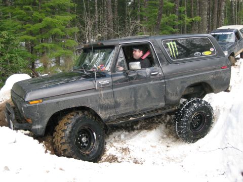 1979 Ford Bronco - A dark 1978 Ford Bronco navigates a snowy trail with another vehicle visible behind it.