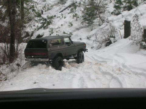 1996 Ford Bronco - Ford Bronco navigating a snowy trail with trees and snow-covered hills in the background.