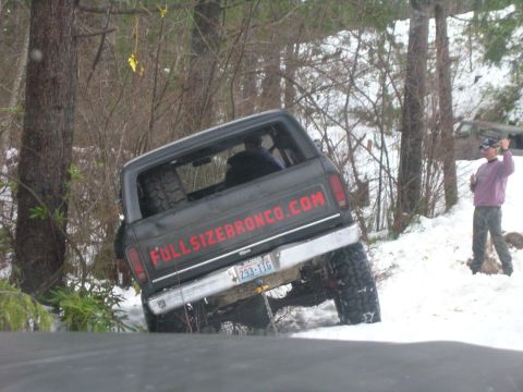 1996 Ford Bronco - A Ford Bronco is partially submerged in snow, with a website address visible on its tailgate.
