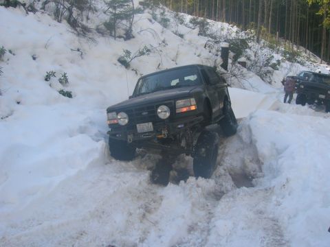 1996 Ford Bronco - A 1996 Ford Bronco navigates a snow-covered trail, with another vehicle visible in the background.