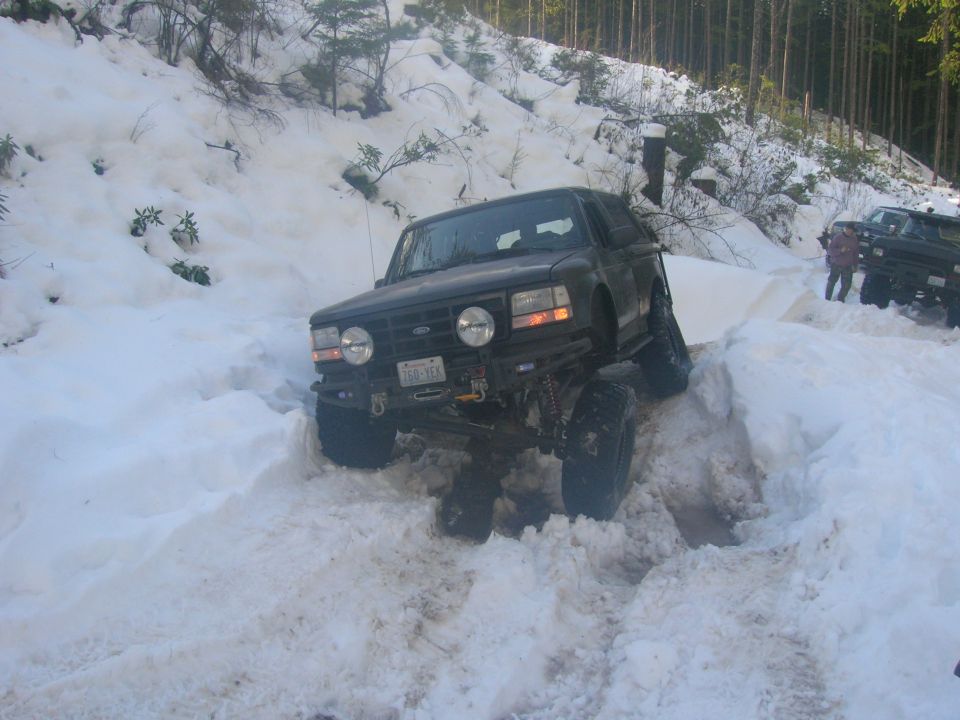 1996 Ford Bronco driving through deep snow, front-mounted winch visible
