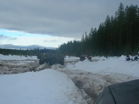 1996 Ford Bronco - Vehicles navigate a snowy and muddy terrain under a cloudy sky.