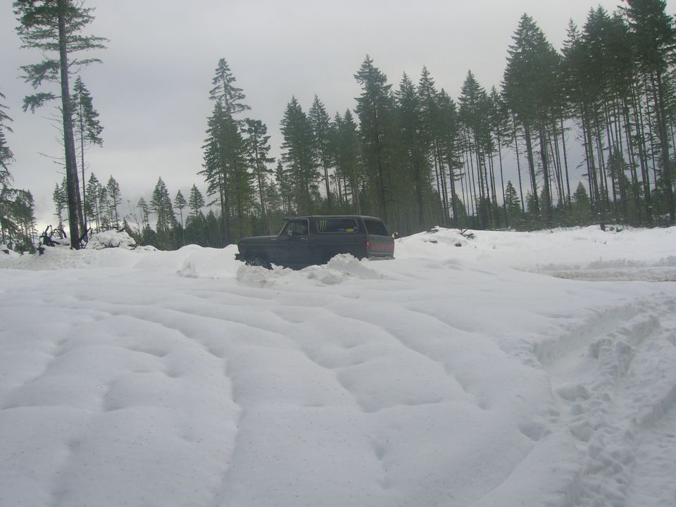 Dark SUV with a boxy body style driving through deep snow