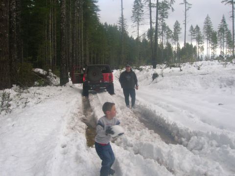 1996 Ford Bronco - A red 1996 Ford Bronco navigates a snowy forest road with two people nearby.