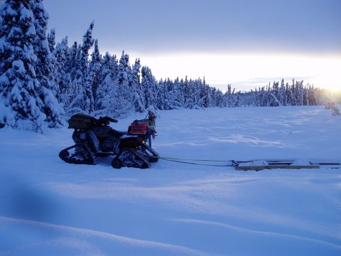 2000 Ford E350 - An ATV equipped with tracks and a sled sits ready for use in a snow-covered landscape.