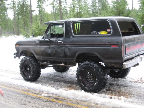 1989 Ford Bronco - This lifted Ford Bronco is parked on a snowy road with trees in the background.