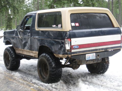1989 Ford Bronco - This lifted Ford Bronco is equipped with large off-road tires and sits in a snowy environment.