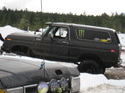 1989 Ford Bronco - A black Ford Bronco, likely a 1978 model, is partially submerged in snow, with another vehicle visible in the foreground.