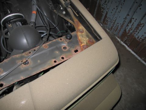1991 Ford LTD Crown Victoria - Close-up view of the engine bay and fender area of a tan vehicle, showing signs of rust.