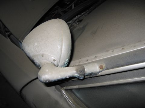 1991 Ford LTD Crown Victoria - A close-up view of a weathered side mirror on a vehicle covered in dust.