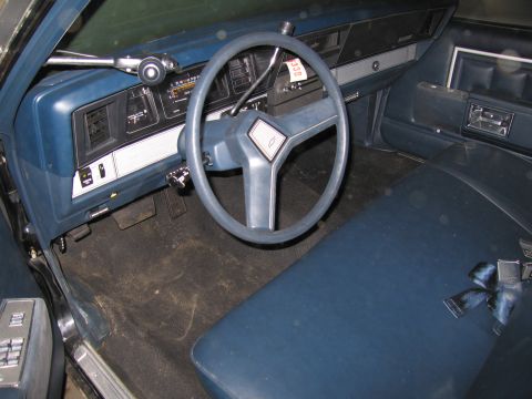 1991 Ford LTD Crown Victoria - The interior of a blue car shows a bench seat, steering wheel, and dashboard with visible gauges and controls.