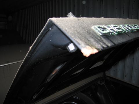 1991 Ford LTD Crown Victoria - The hood of a car, showing a Chevrolet emblem, is open inside a storage unit.