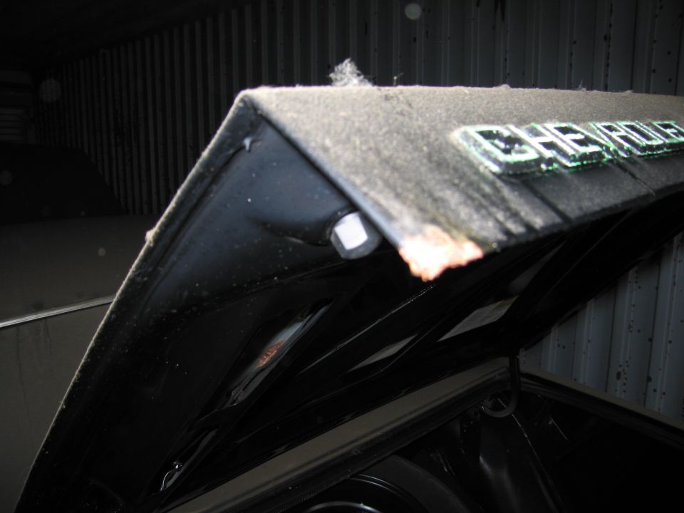 Hood of a car with a 'CHEVROLET' emblem. Another vehicle is visible in the background