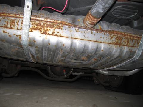 1991 Ford LTD Crown Victoria - The underside of a vehicle reveals a heavily rusted fuel tank and associated exhaust components.