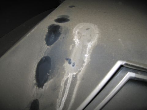 1991 Ford LTD Crown Victoria - A close-up view of a dusty surface with several dark stains and white streaks, possibly indicating leaks or spills.