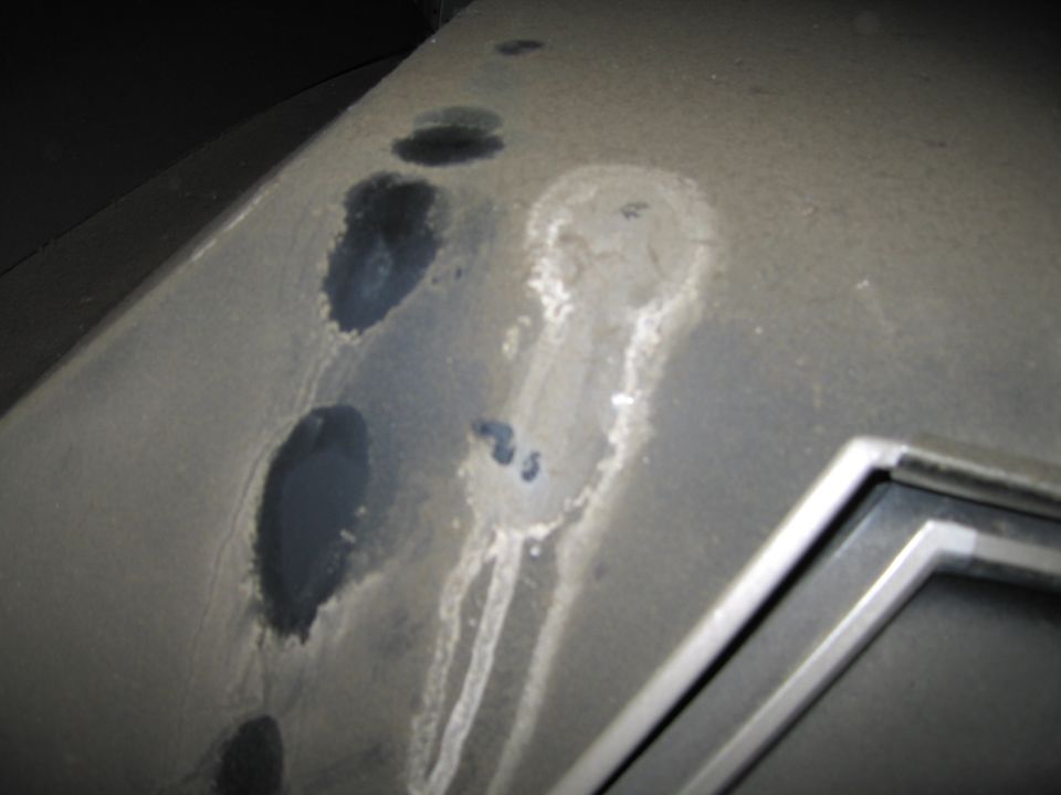 Dusty surface with dark stains and streaks, showing a corner of a metallic trim