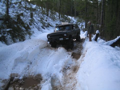 1989 Ford Bronco - A Ford Bronco drives through a challenging snowy path in a wooded area.