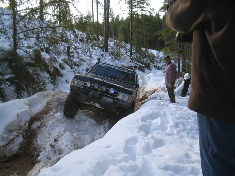 1989 Ford Bronco - A black 1989 Ford Bronco navigates a snowy, wooded trail, displaying "BIG BRONCOS 4x4 CLUB" on its windshield.