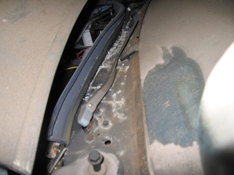 1991 Ford LTD Crown Victoria - Close-up view of the wiper mechanism and surrounding cowl area, showing wear and some debris.