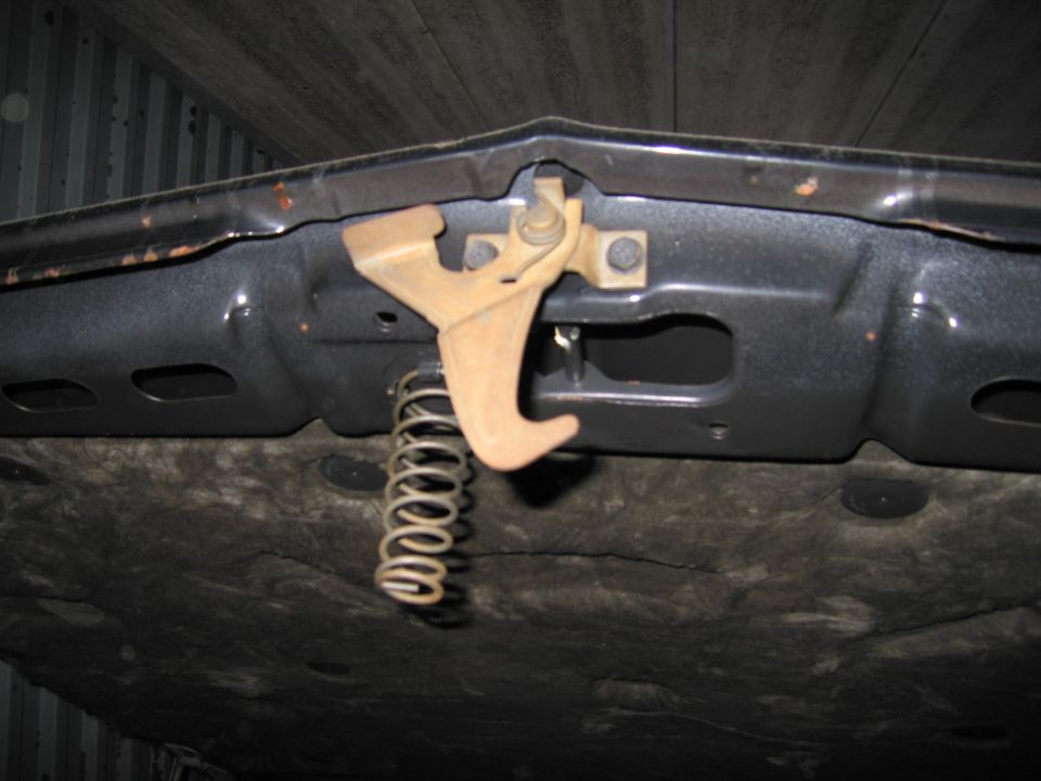Close-up of a hood latch mechanism with a spring