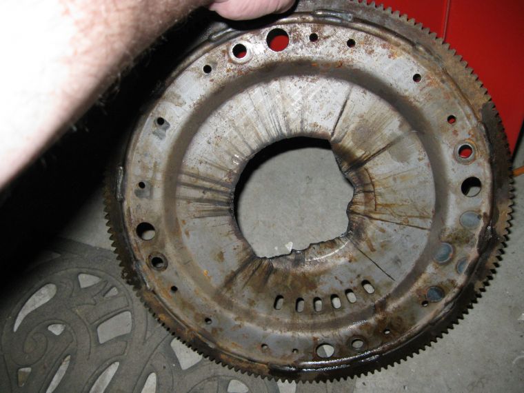 Damaged transmission flexplate with torn metal around the center opening