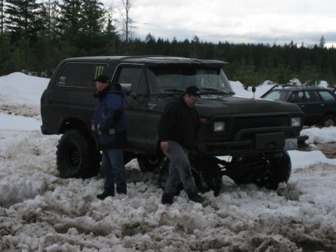 1979 Ford Bronco - A lifted 1979 Ford Bronco sits in the snow, with two people standing nearby and another vehicle in the background.