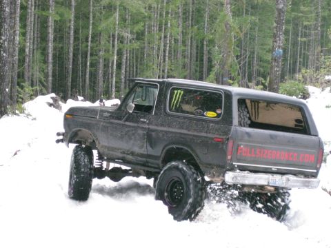 1979 Ford Bronco - A lifted 1978 Ford Bronco navigates a snowy forest road, its off-road capabilities evident.