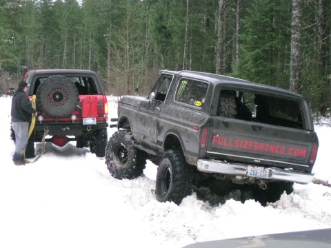 1979 Ford Bronco - Two Ford Broncos navigate a snowy trail, with one appearing stuck in the snow.