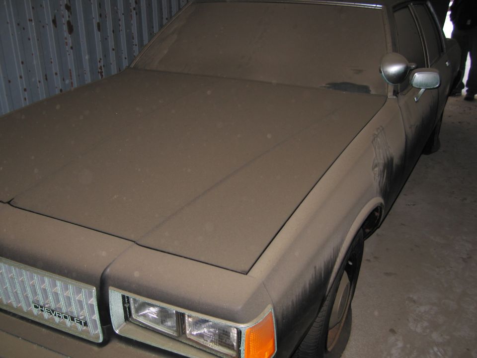 Dusty Chevrolet Caprice in a garage, front grille visible with 'CHEVROLET' text