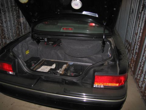 1991 Ford LTD Crown Victoria - The trunk of a 1991 Ford Crown Victoria LTD is open, revealing installed equipment and a battery.
