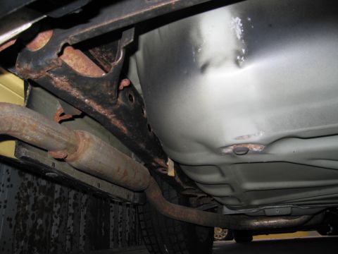 1991 Ford LTD Crown Victoria - Close-up of the undercarriage, revealing significant rust on the frame and exhaust system.