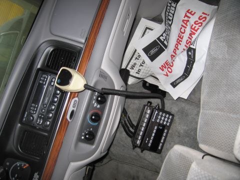 1991 Ford LTD Crown Victoria - The interior of a police vehicle shows a radio microphone, control panel, and various documents on the passenger seat.