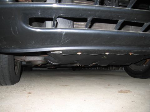 1991 Ford LTD Crown Victoria - Underside view of a car's front bumper and splash shield, showing the protective plastic underneath.
