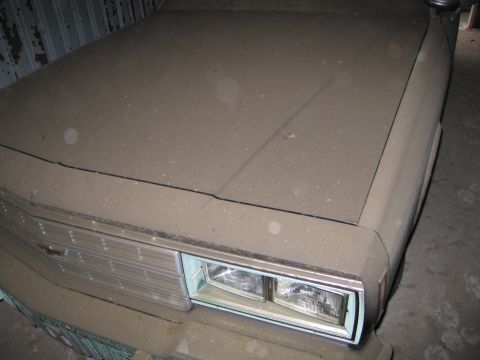 1991 Ford LTD Crown Victoria - A car covered in dust sits in what appears to be a garage or storage unit.