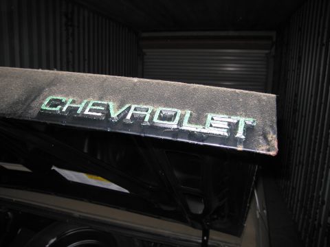 1991 Ford LTD Crown Victoria - The Chevrolet emblem is visible on the hood of a car stored indoors.