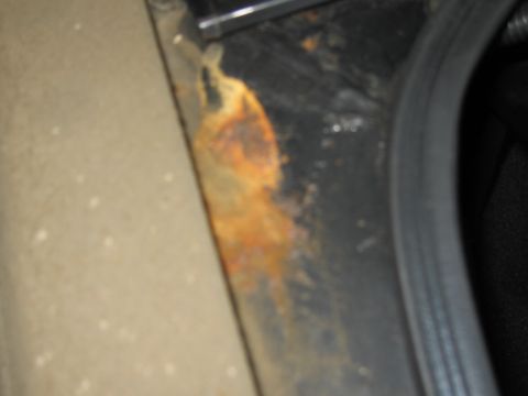 1991 Ford LTD Crown Victoria - Rust is visible on the metal frame of a vehicle, adjacent to a black rubber seal.