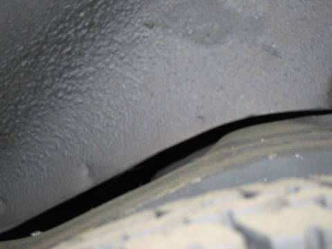 1991 Ford LTD Crown Victoria - A close-up view of the interior of a vehicle's wheel well, showing textured surfaces and a portion of the tire.
