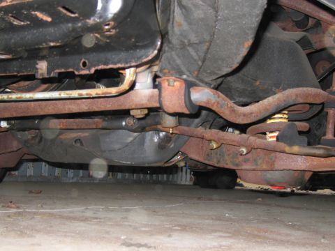 1991 Ford LTD Crown Victoria - The undercarriage of a vehicle shows significant rust on its suspension and exhaust components.