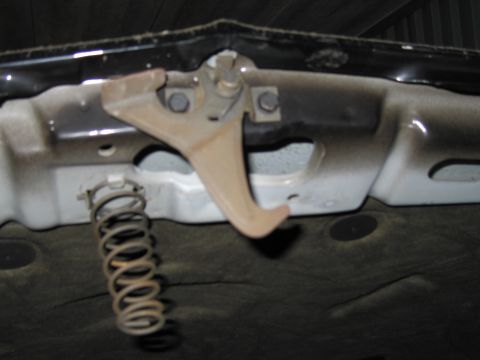 1991 Ford LTD Crown Victoria - Close-up view of a vehicle's hood latch mechanism and a coiled spring.