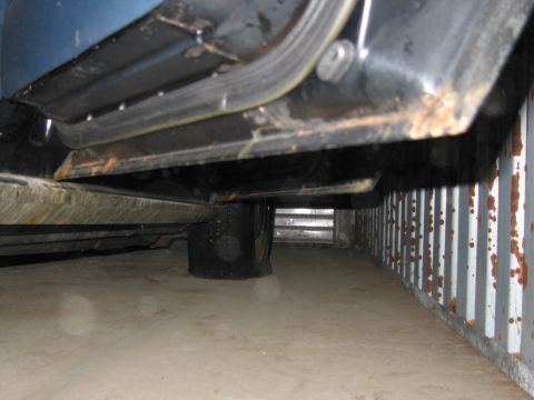 1991 Ford LTD Crown Victoria - Close-up of a vehicle's undercarriage, revealing rust and a flat tire.