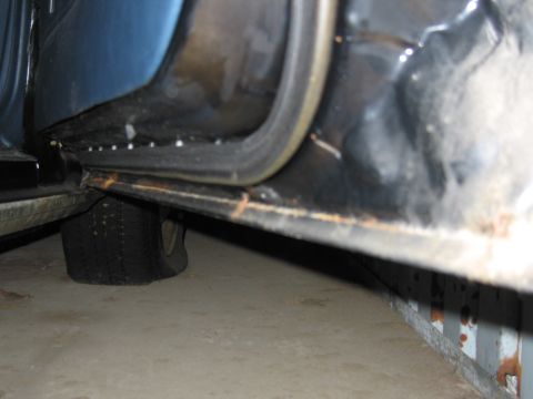 1991 Ford LTD Crown Victoria - Close-up view of a vehicle's door sill and a flat tire, suggesting it is in storage or disrepair.