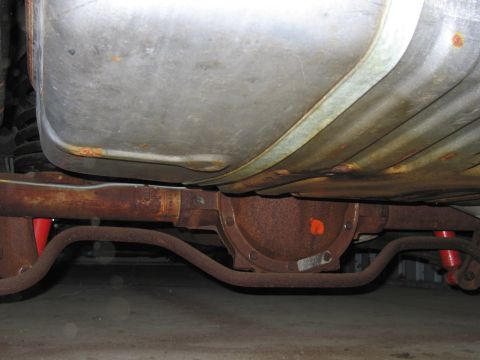 1991 Ford LTD Crown Victoria - The underside of a vehicle reveals significant rust on the differential and fuel tank, with visible suspension parts.