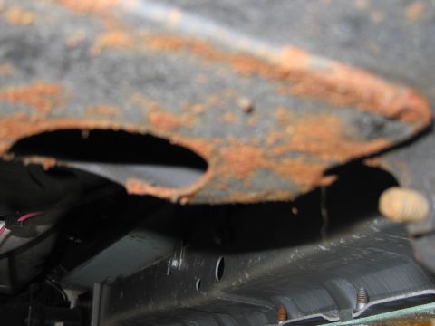 1991 Ford LTD Crown Victoria - Rusted frame section with visible holes and underside components.