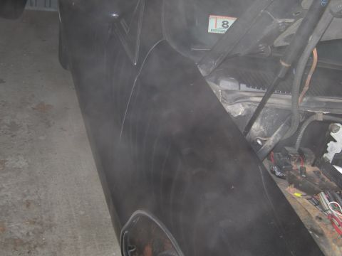 1991 Ford LTD Crown Victoria - black painted fender panel leans in a garage with engine-bay components and wiring visible behind it.