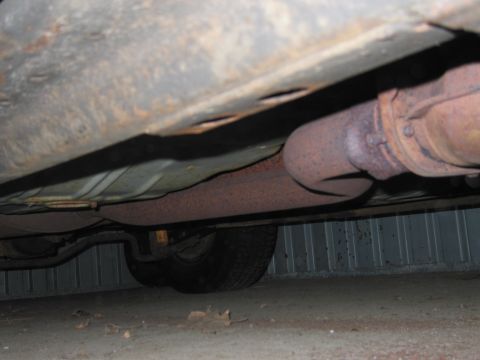 1991 Ford LTD Crown Victoria - The underside of a vehicle is visible, with significant rust on the exhaust system and frame.