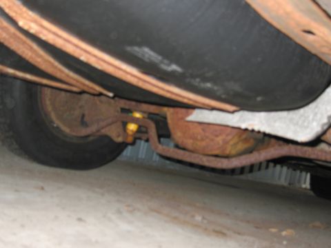 1991 Ford LTD Crown Victoria - The underside of a vehicle shows significant rust on its suspension components and exhaust system.