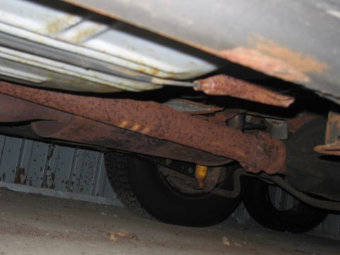1991 Ford LTD Crown Victoria - Photograph of a vehicle's rusted rear suspension, axle, and tire from underneath.