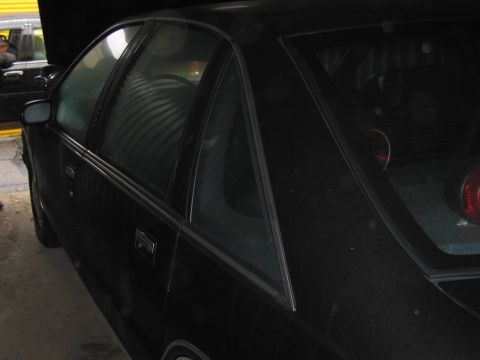 1991 Ford LTD Crown Victoria - Photograph of the rear quarter and window of a black coupe in a garage.