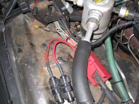 1991 Ford LTD Crown Victoria - Photograph of engine-bay wiring, connectors, and a component with red and green hoses.